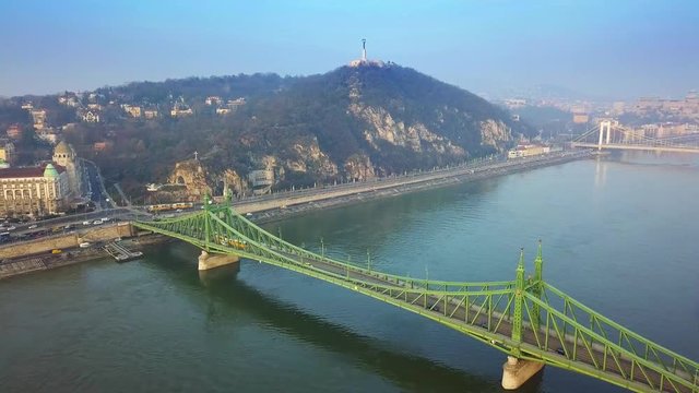 Budapest, Hungary - Drone flying over Liberty Bridge (Szabadsag Hid) towards Gellert Hill and Statue of Liberty with traditional yellow tram going on it