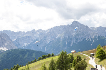 Fototapeta na wymiar paragliding in the Italian Alps with tourists coming down the valley