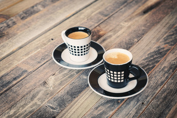 Two small coffee cups on wooden background