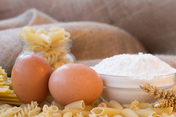 Dry spaghetti pasta tied up with rope and burlap bag of wheat grains