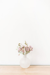 Wild flowers in front of white wall. Minimal composition.