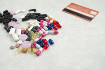 Many colorful pills medicine with credit card on a white background