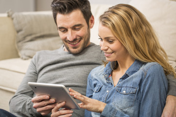 cheerful couple in living room using a digital tablet