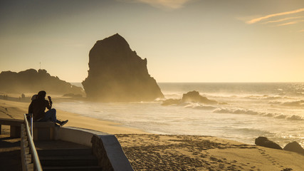 couple of lovers at sunset on a beach with rocks in the background. Portugal