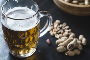 Glass of beer and peanuts on the wooden background