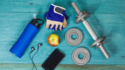 Weight plates, gloves and smartphone on wooden background