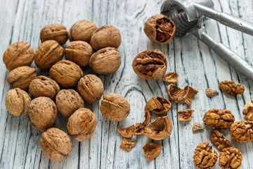 Whole walnuts on a white wooden background with nectic cutters.