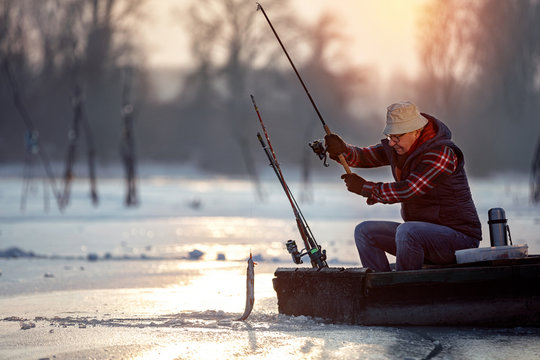 fisherman fishing on ice at the sunrise