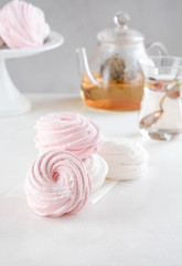Homemade zephyr or marshmallow in white plate with cup of tea on white table. Marshmallow, Meringue, Zephyr. Valentine's or Mothers Day concept.