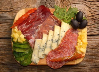  Blue cheese and cold meat platter with salami, slices ham prosciutto, cheese, olives and herbs