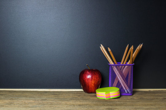 Red apple and stationery on wood table with Blackboard (Chalk Board) as background with copy space. Education and Back to school concept.