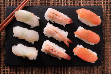 Sushi japanese japan food various selection raw fish salmon prawn shrimp in a row line with chopstick on a black slate tray or platter photo
