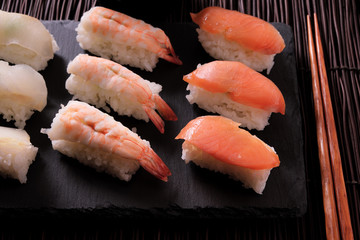 Sushi japanese japan food various selection raw fish salmon prawn shrimp in a row line with chopstick on a black slate tray or platter photo
