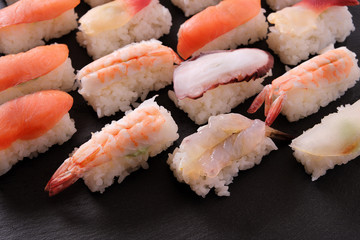 Sushi japanese japan food various selection raw fish salmon prawn shrimp in a row line on a black slate tray or platter photo