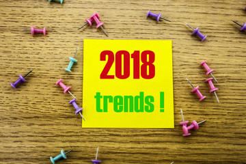 Trends 2018 text on yellow sticky note on wooden background. Minimal concept.