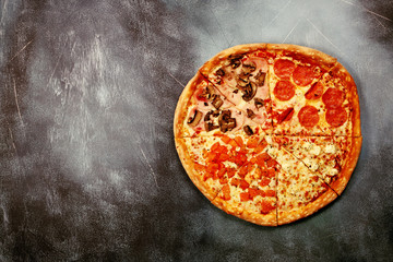Slices of pizza with different toppings on a dark textured background