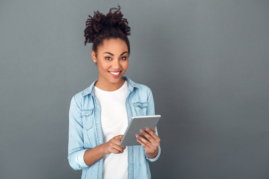 Young African Woman Isolated On Grey Wall Studio Casual Daily Lifestyle Holding Digital Tablet