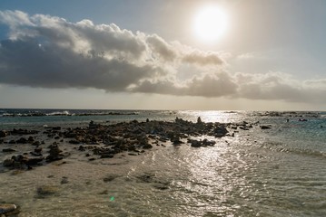 Fototapeta na wymiar pebble beach and ocean waves on the sea of the Caribbean island of Aruba