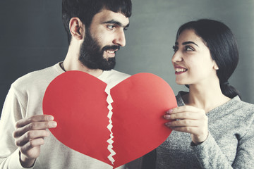 Cropped hands of couple holding cracked red heart