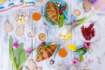 Easter breakfast flat lay with, bread toast with fried egg and gre, colored quail eggs and spring holidays decorations. Top view. Copy space. croissants for breakfast. Free space for text or postcard.