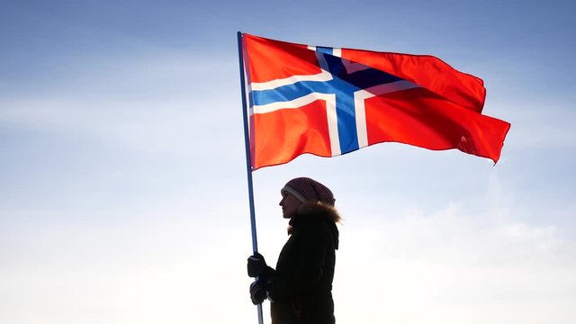 Woman with the flag of Norway against the blue sky. Fan support of national team