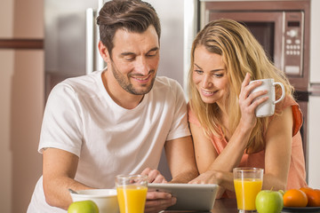 young couple using digital tablet at breakfast time