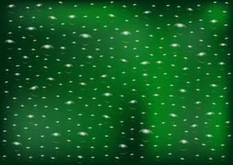 Drops of rain on an evening summer day on a glass of trees blurred green background.