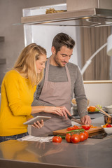 Attractive couple in home kitchen with digital tablet