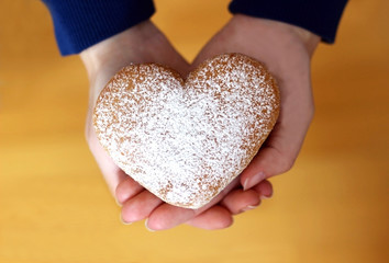 donut in heart shape in the hands of a woman