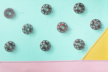 Collage of metal bobbin spools on seamed fabrics in pastel tones - trendy decoration with flat shadows