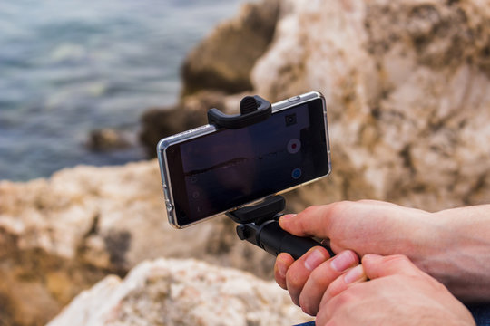 Man holding a smart phone filming the beach in Villefranche-sur-mer, France