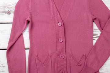 Female pink cardigan with buttons. Women sweater with pockets on wooden background. Female high quality garment.