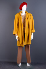 Mannequin dressed in yellow elegant topcoat. Fashion autumn outfit on female mannequin, grey background. Feminine trendy apparel. New collection of female autumn clothing.