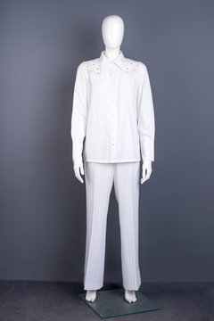 Full length mannequin in white apparel. Women long sleeve blouse and trousers on mannequin. Female garment store.