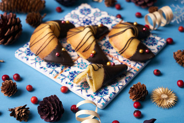 Traditional Chinese fortune cookies. Delicious chocolate Fortune cookies on a blue background with Christmas decorations, close-up