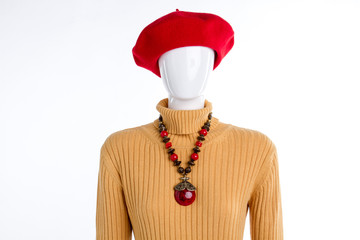 Red beret, necklace and yellow sweater. Female mannequin dressed in pullover and red beret, isolated on white background. Ladies clothes and accessories.