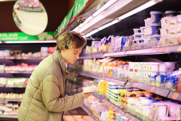 Man shopping in supermarket, reading product information