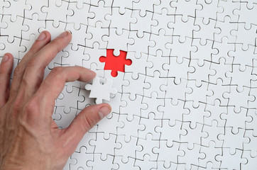 The texture of a white puzzle puzzle in the assembled state with one missing element that the male...