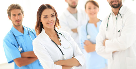 Fototapeta premium Attractive female doctor with medical stethoscope in front of medical group