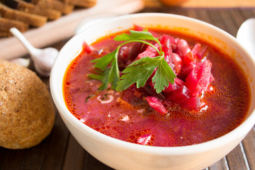 Traditional Ukrainian Russian vegetable soup borscht, with hard cream. parsley rye bread rolls, on black table