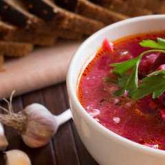 Traditional Ukrainian Russian vegetable soup borscht, with hard cream. parsley rye bread rolls, on black table