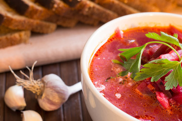 Traditional Ukrainian Russian vegetable soup borscht, with hard cream. parsley rye bread rolls, on black table