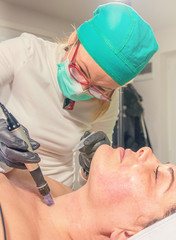 Beautician performs a needle mesotherapy treatment on a woman face.