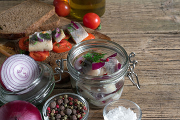 Fototapeta na wymiar homemade pickled herring fillet in a jar and sandwiches with herring and tomatoes
