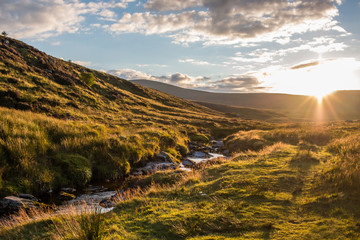 Beautiful, cloudy sunset over a small river flowing through green, grass covered hills in Wicklow...