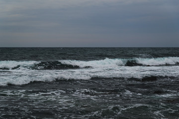 Storm on the sea in cloudy weather at sunset