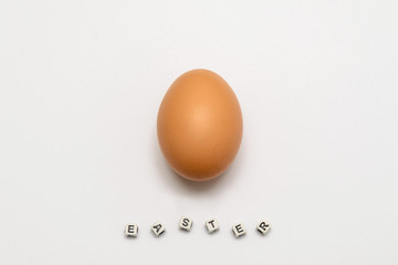 Chicken egg of light brown color on a white background with an Easter inscription