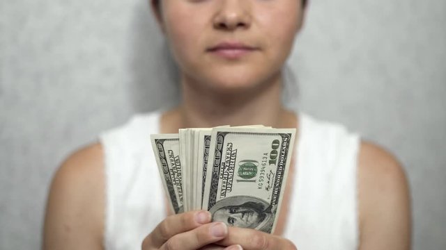 Smiling girl on background of dollars. Pleasure, joy. Close-up