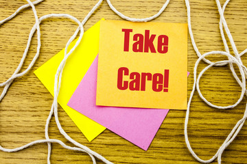 Take care- word on yellow sticky note in wooden background. Bussines concept.