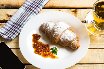 Breakfast with herbal tea and croissant on wooden vintage table